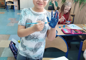 chłopiec z dłonią pomalowaną na niebiesko